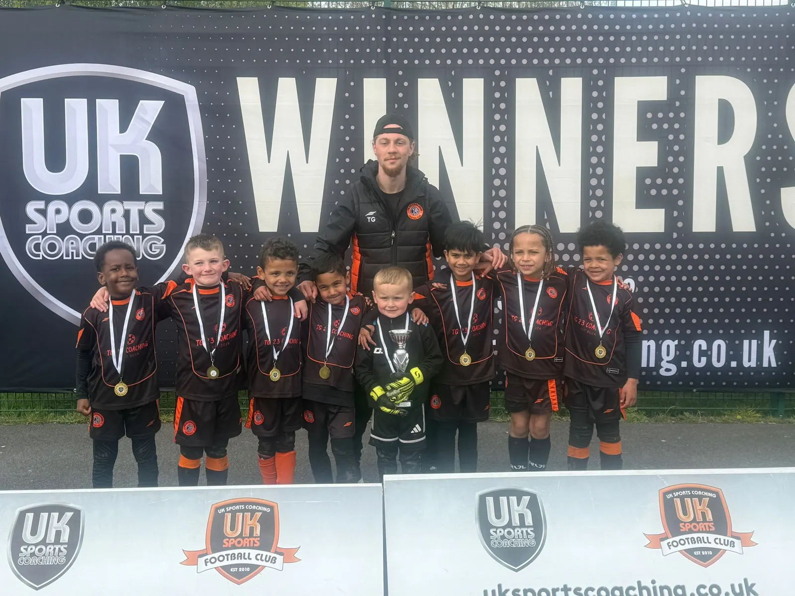 TG23 players and coach with medals and a trophy at a UK Sports Coaching winners display